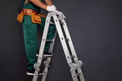 Professional constructor climbing ladder on black  background, closeup