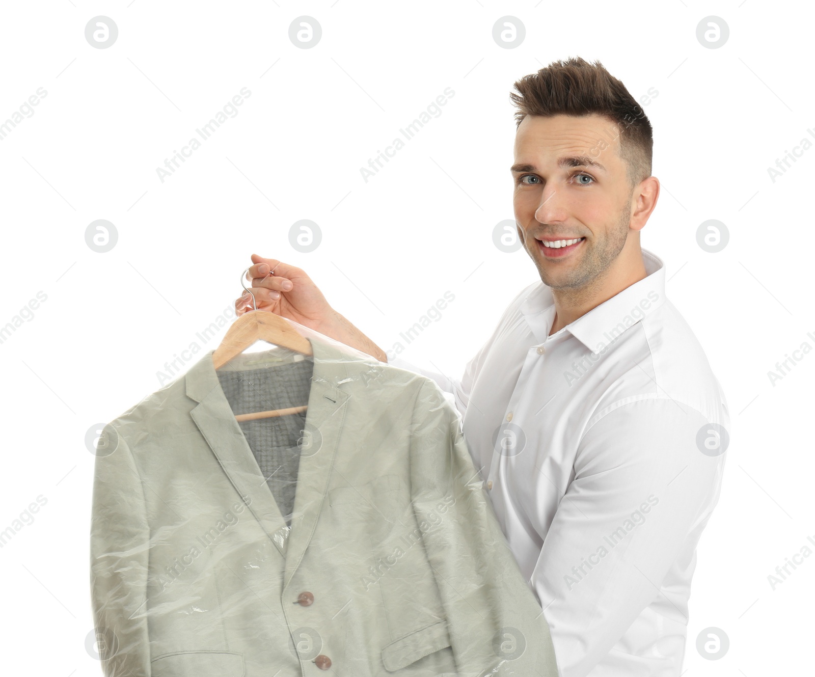 Photo of Man holding hanger with jacket in plastic bag on white background. Dry-cleaning service