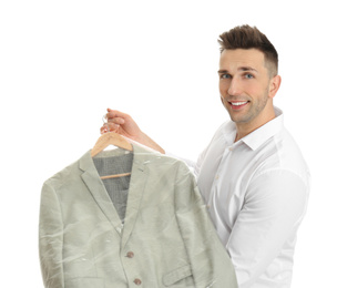 Man holding hanger with jacket in plastic bag on white background. Dry-cleaning service