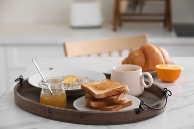 Photo of Wooden tray with delicious breakfast on white marble table in kitchen, space for text