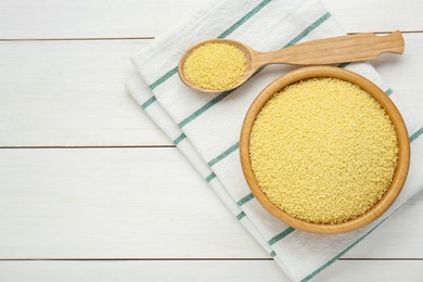 Photo of Bowl and spoon with raw couscous on white wooden table, top view. Space for text