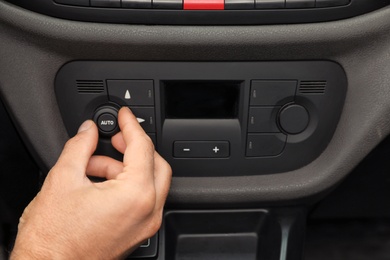 Photo of Man adjusting air conditioner in car, closeup