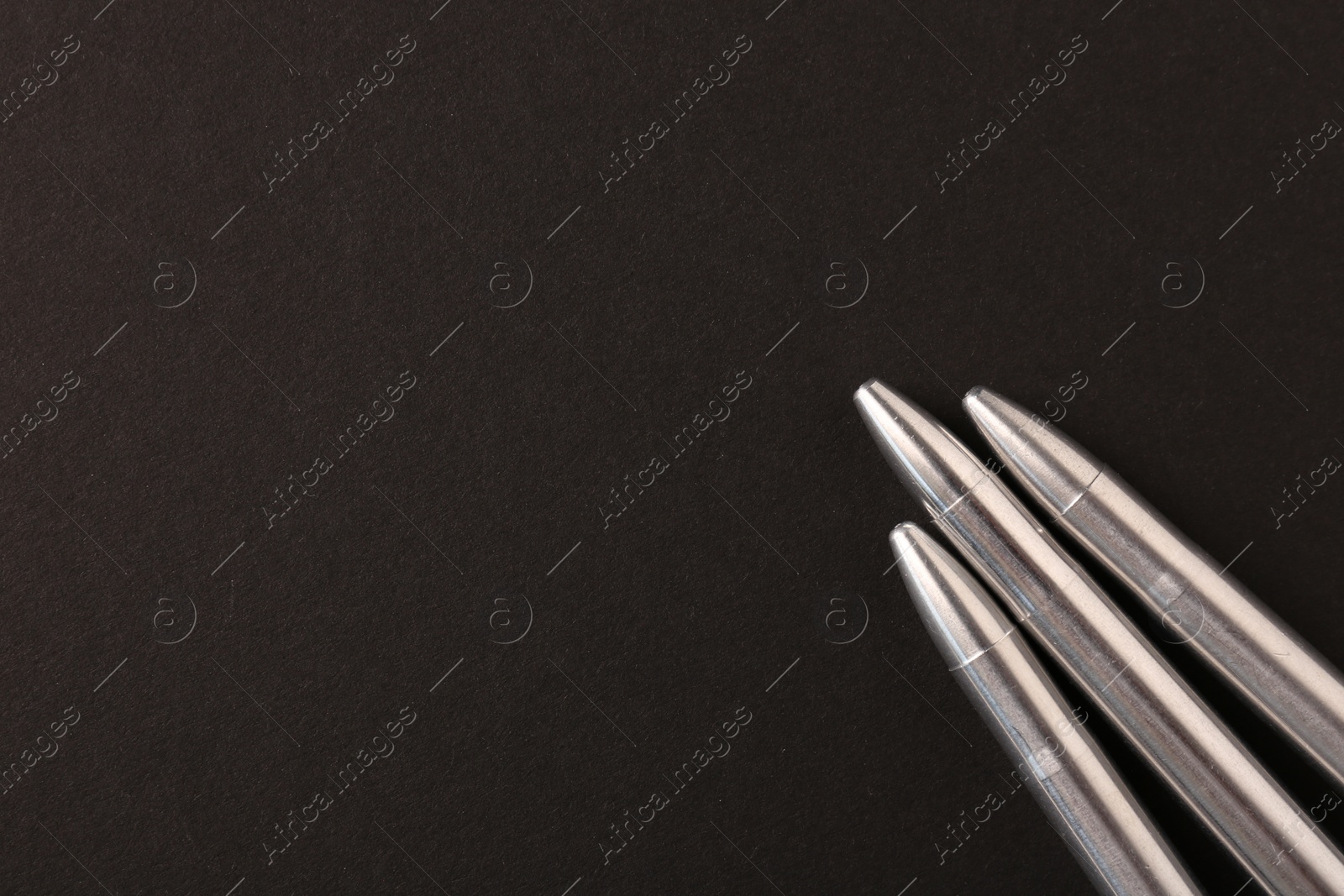Photo of Three metal bullets on black background, flat lay. Space for text