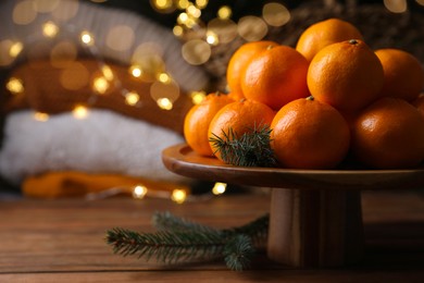 Photo of Stand with delicious ripe tangerines and fir twigs on wooden table. Space for text