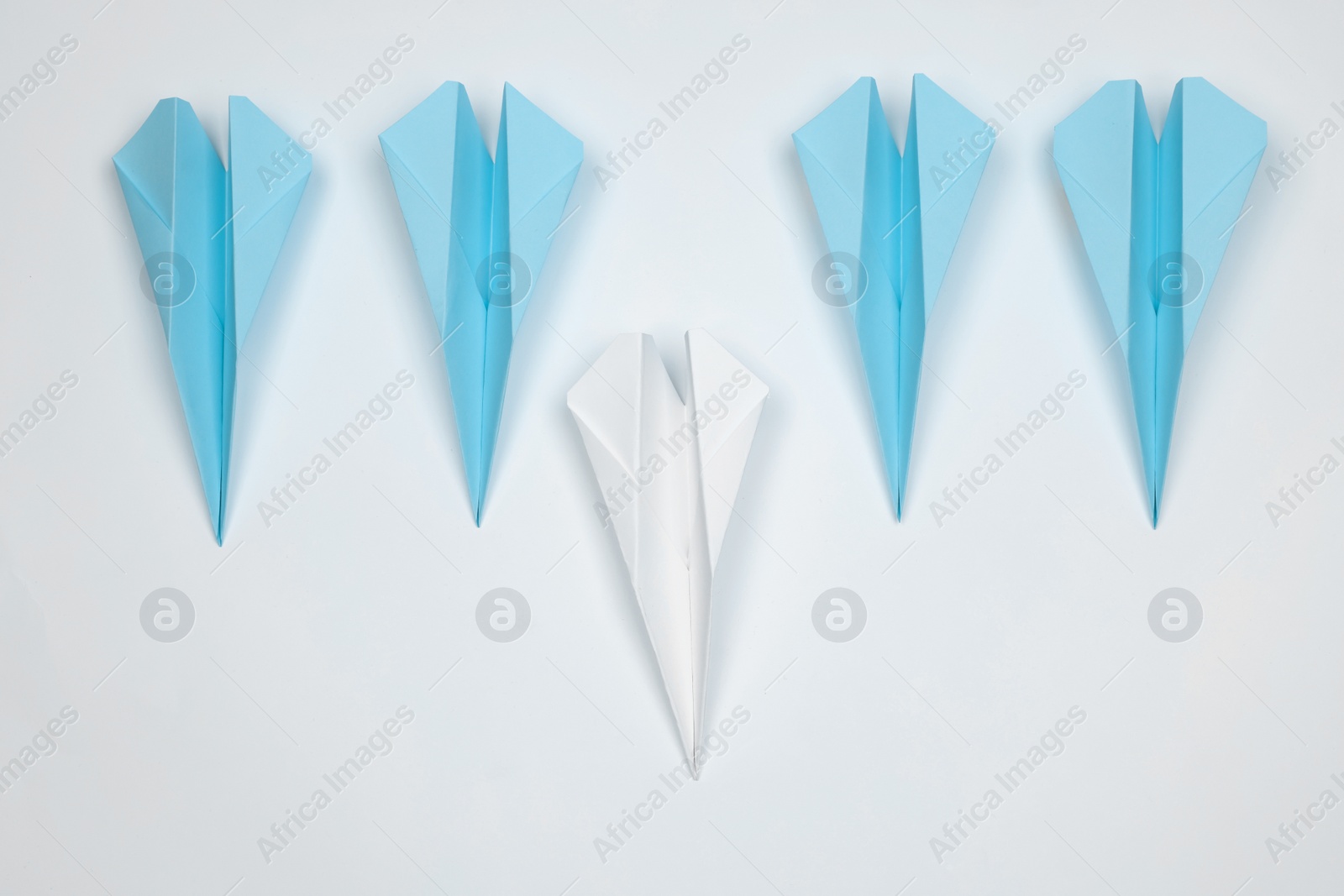 Photo of Handmade colorful paper planes on white table, flat lay. Leadership concept