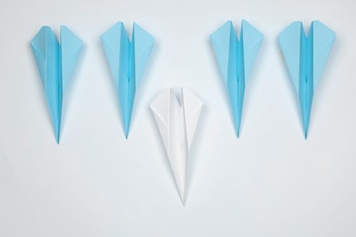 Photo of Handmade colorful paper planes on white table, flat lay. Leadership concept