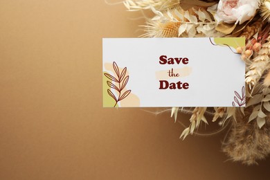 Beautiful card with Save the Date phrase and dry flowers on beige background, top view. Space for text