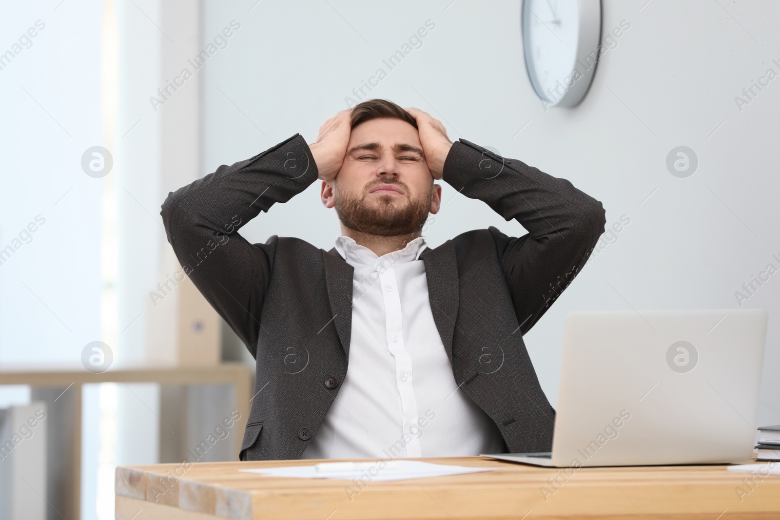 Photo of Man suffering from migraine at workplace in office