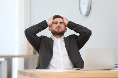 Man suffering from migraine at workplace in office