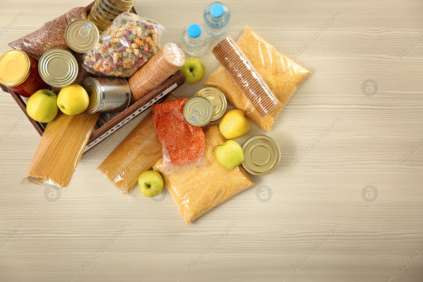 Photo of Donation box and different products on wooden table, top view. Space for text