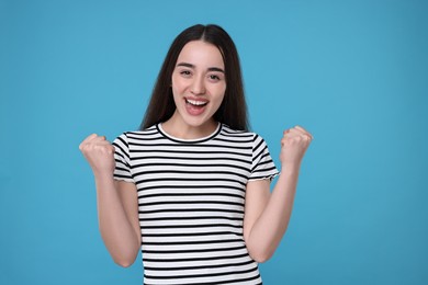 Portrait of happy surprised woman on light blue background