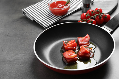 Photo of Melting ice cubes with tomatoes, oil and rosemary on grey table