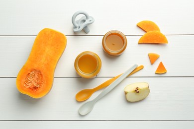 Tasty baby food in jars, pacifier and ingredients on white wooden table, flat lay