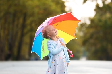 Cute little girl with bright umbrella on street