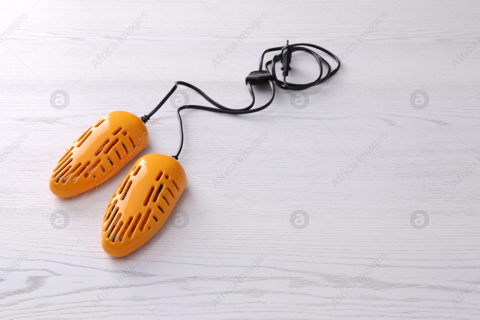 Photo of Electric shoe dryer on white wooden background, space for text