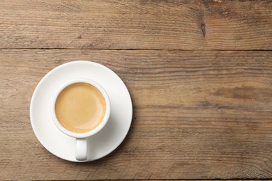 Photo of Aromatic coffee in cup on wooden table, top view. Space for text