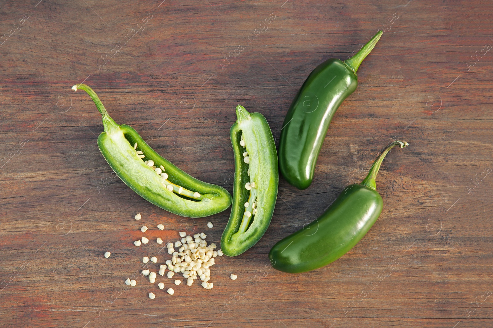 Photo of Fresh green jalapeno peppers and seeds on wooden table, flat lay