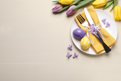 Photo of Festive Easter table setting with eggs on beige background, flat lay. Space for text