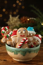 Delicious homemade Christmas cookies in bowl on wooden table against blurred festive lights