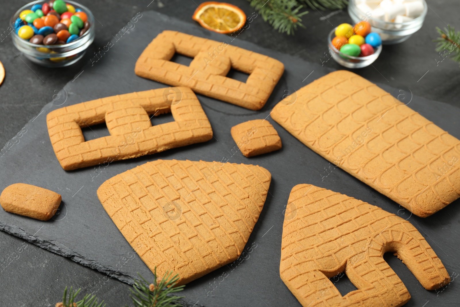 Photo of Parts of gingerbread house on black table, closeup