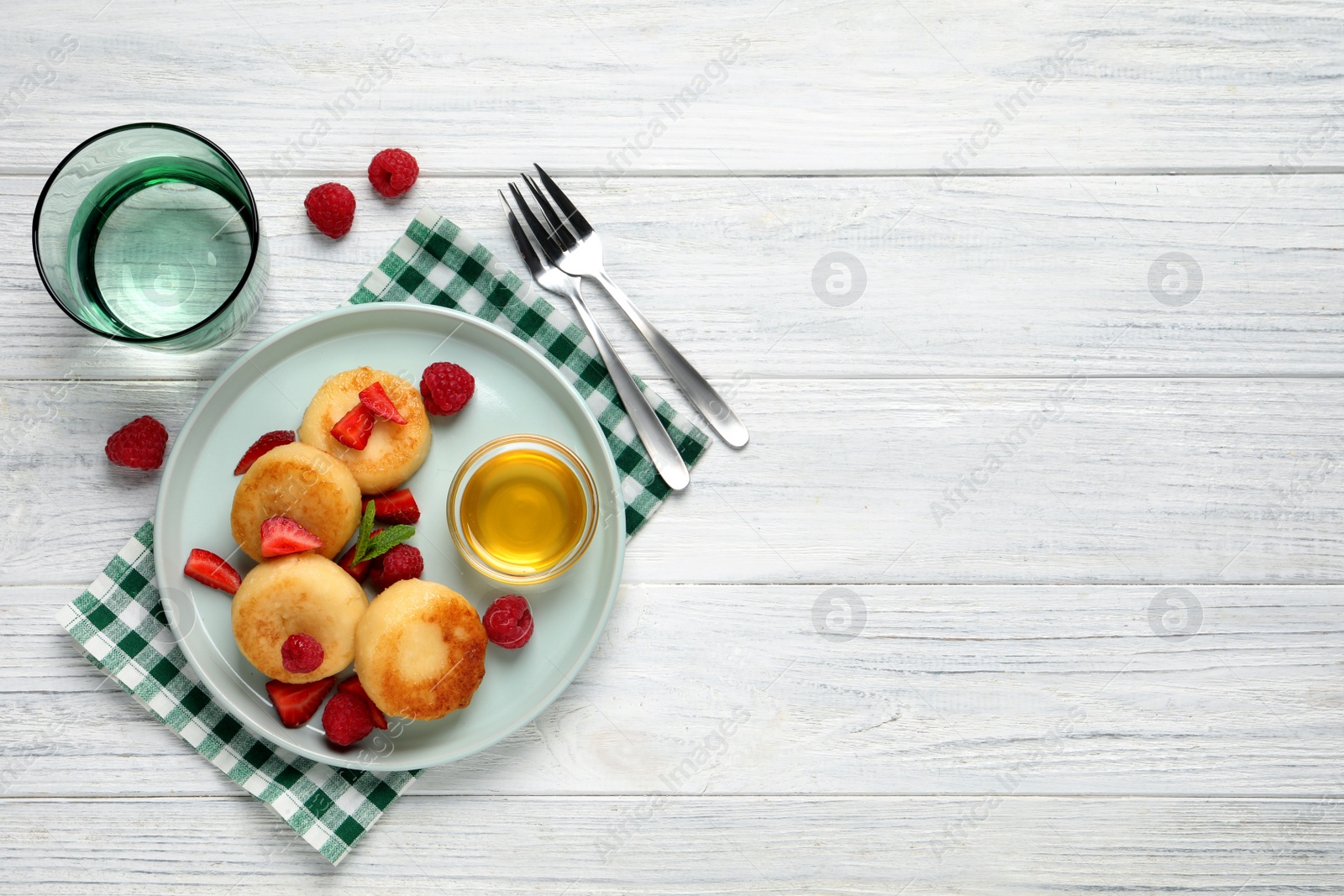 Photo of Delicious cottage cheese pancakes with fresh berries and honey on white wooden table, flat lay. Space for text