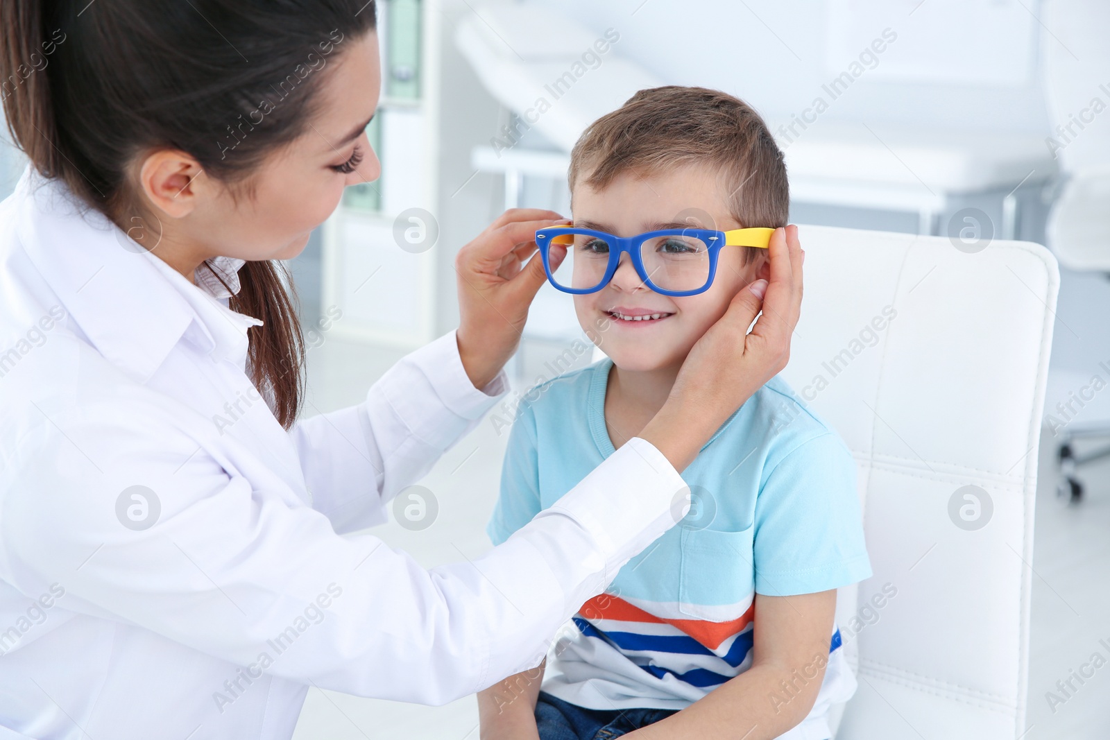 Photo of Children's doctor putting glasses on little boy in clinic