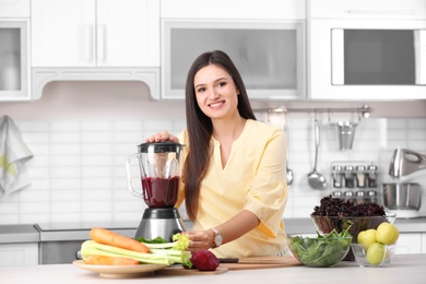 Young woman preparing tasty healthy smoothie at table in kitchen