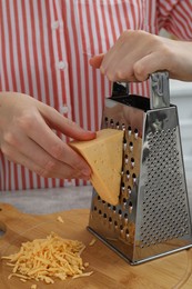 Woman grating cheese at kitchen table, closeup