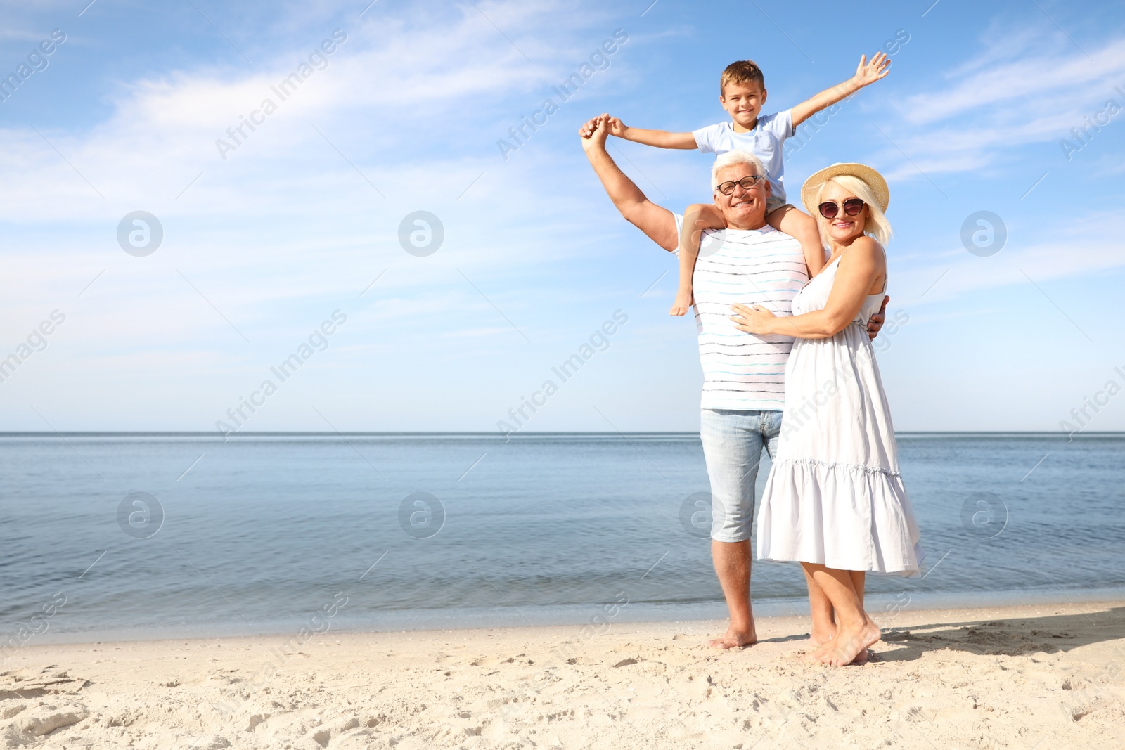 Photo of Cute little boy with grandparents spending time together on sea beach