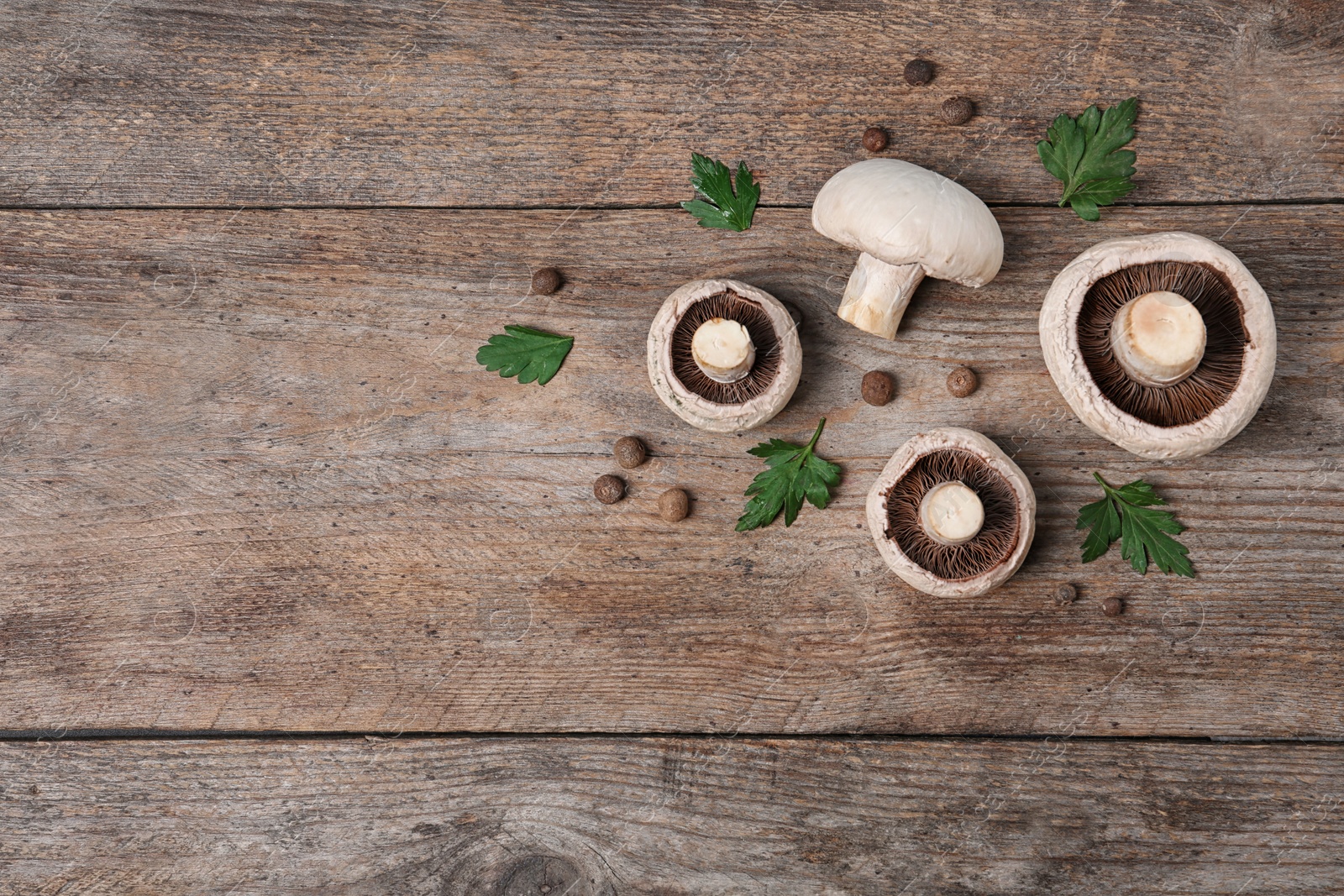 Photo of Flat lay composition with fresh champignon mushrooms on wooden background, space for text
