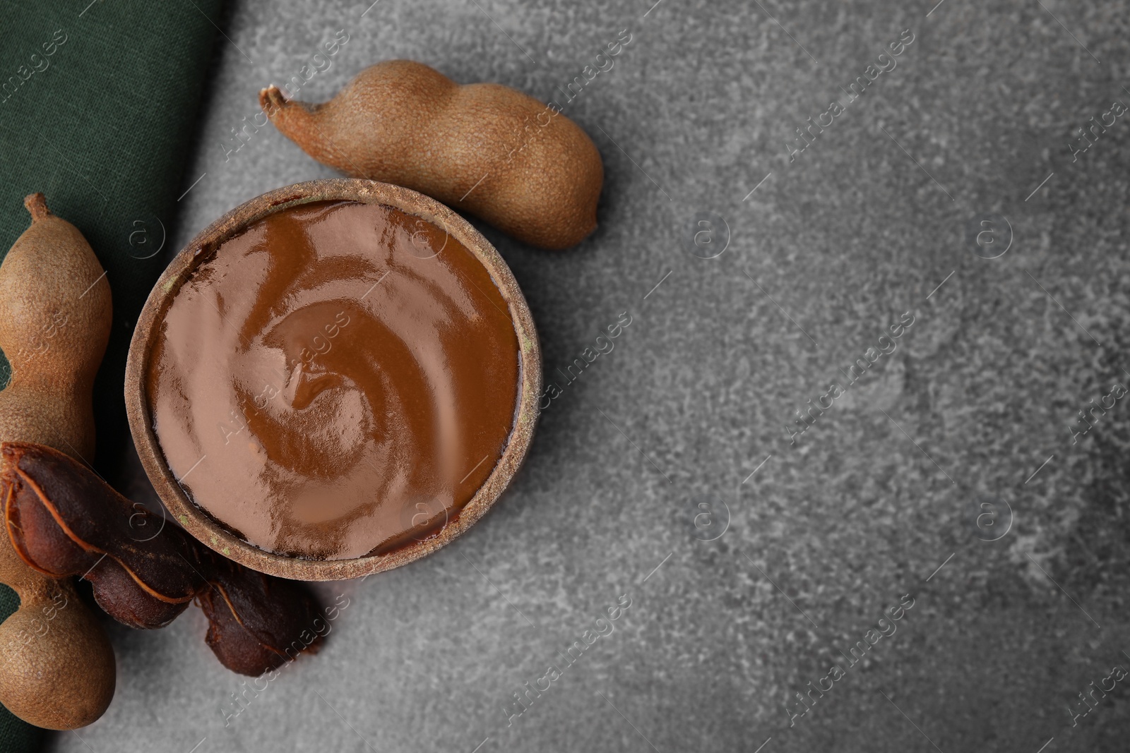 Bowl of tamarind sauce and fresh pods on brown table, flat lay. Space for text Photo of Bowl of tamarind sauce and fresh pods on brown table, flat lay. Space for text