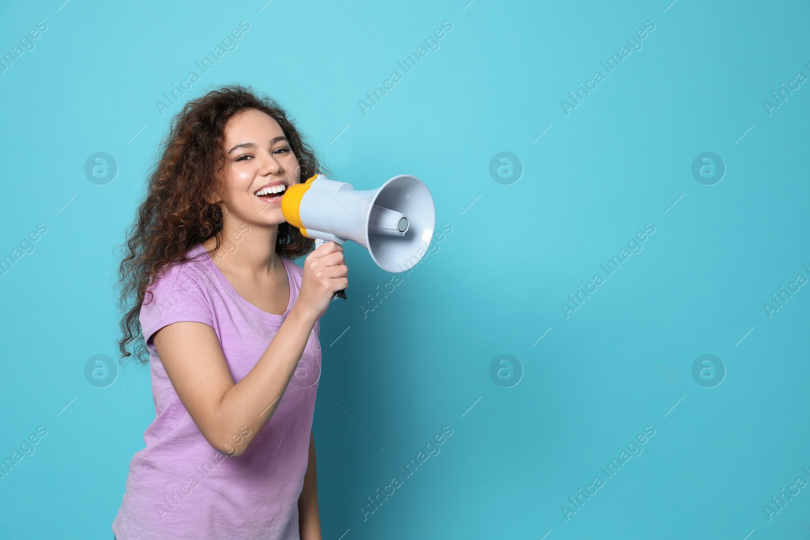 Photo of Young African-American woman with megaphone on color background. Space for text