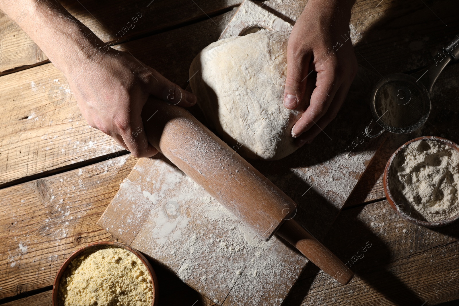 Photo of Man making dough at wooden table, top view