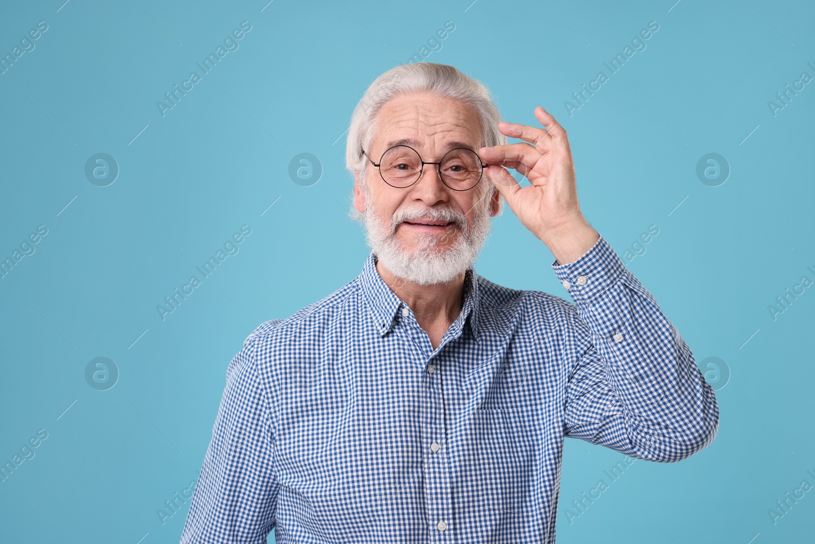 Photo of Portrait of stylish grandpa with glasses on light blue background