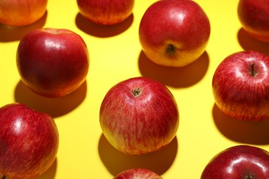 Photo of Ripe red apples on yellow background, closeup