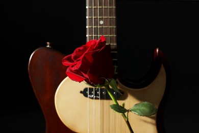 Photo of Beautiful rose and electric guitar on black background, closeup