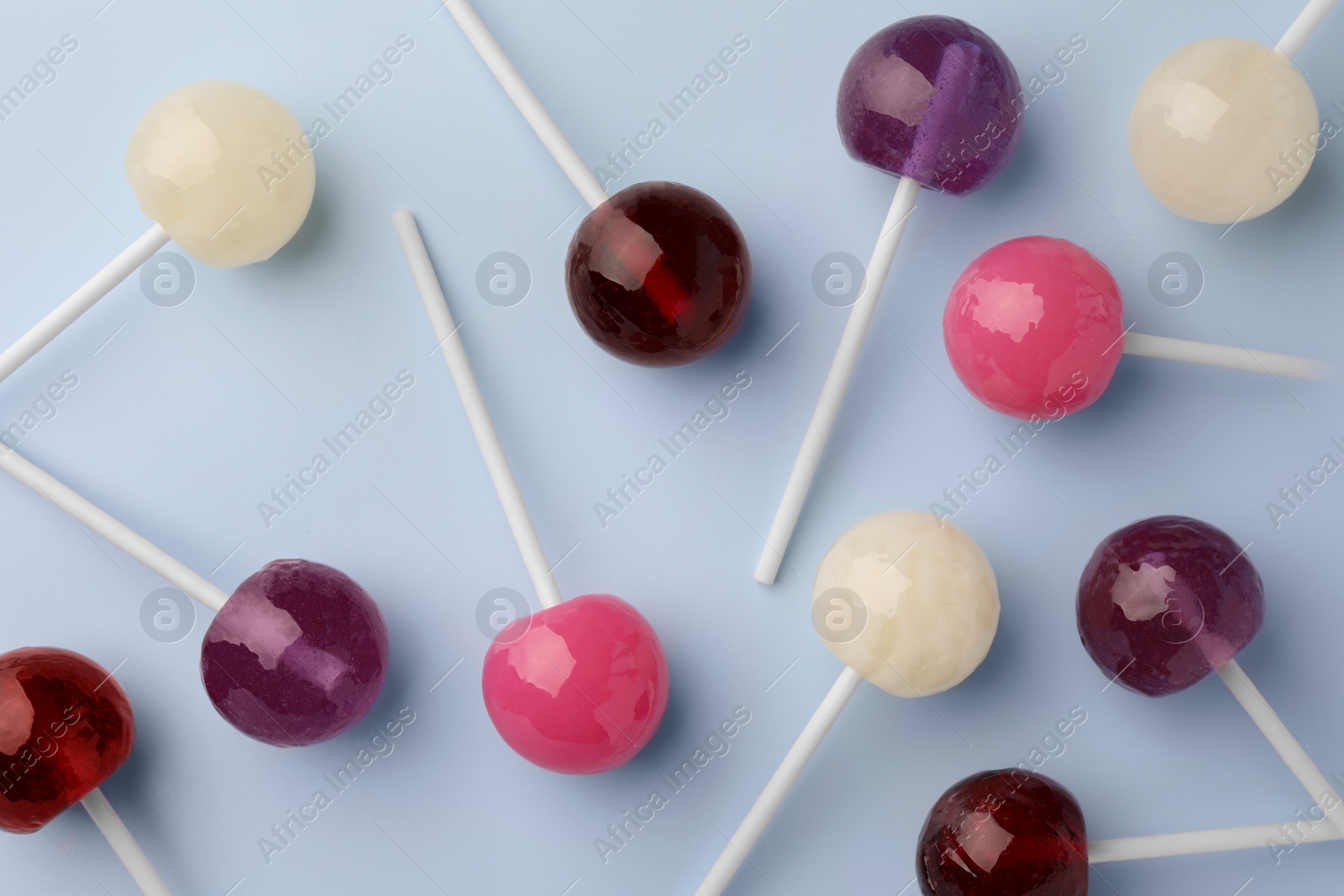 Photo of Many tasty lollipops on light blue background, flat lay