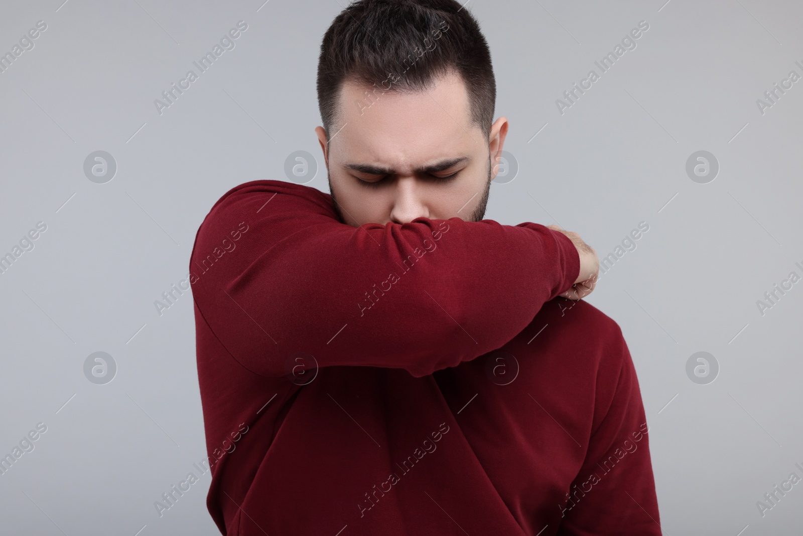 Photo of Sick man coughing on gray background. Cold symptoms