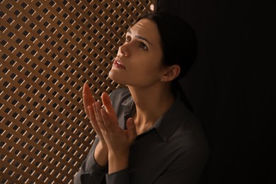 Woman praying to God during confession in booth