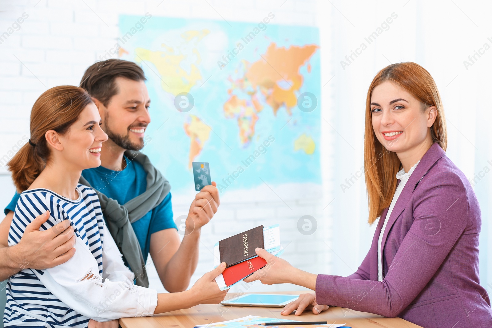 Photo of Female manager giving passports with tickets to couple in travel agency