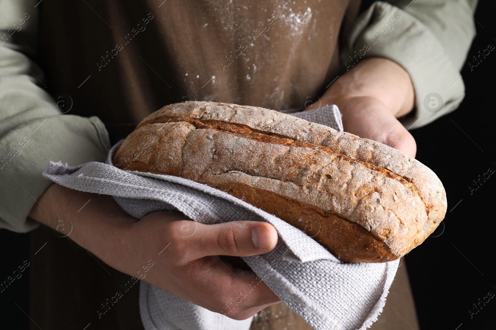 Photo of Woman holding freshly baked bread on black background, closeup