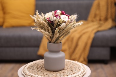 Bouquet of beautiful dry flowers and spikelets in vase on side table at home