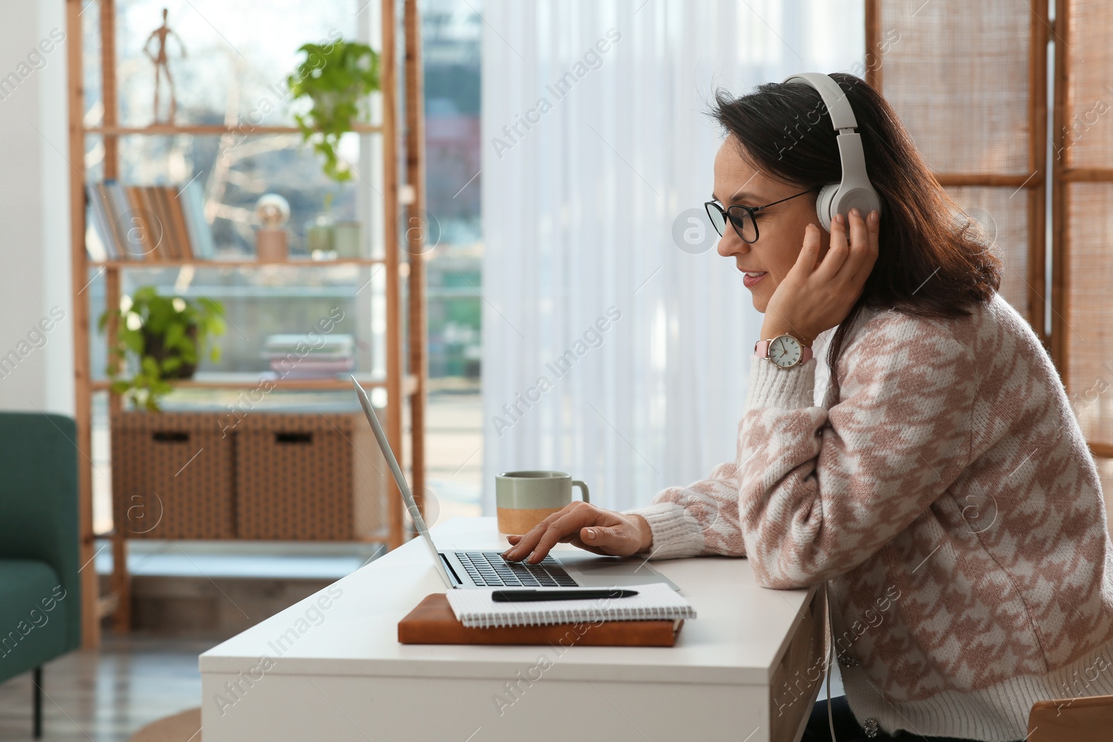 Photo of Woman with modern laptop and headphones learning at home