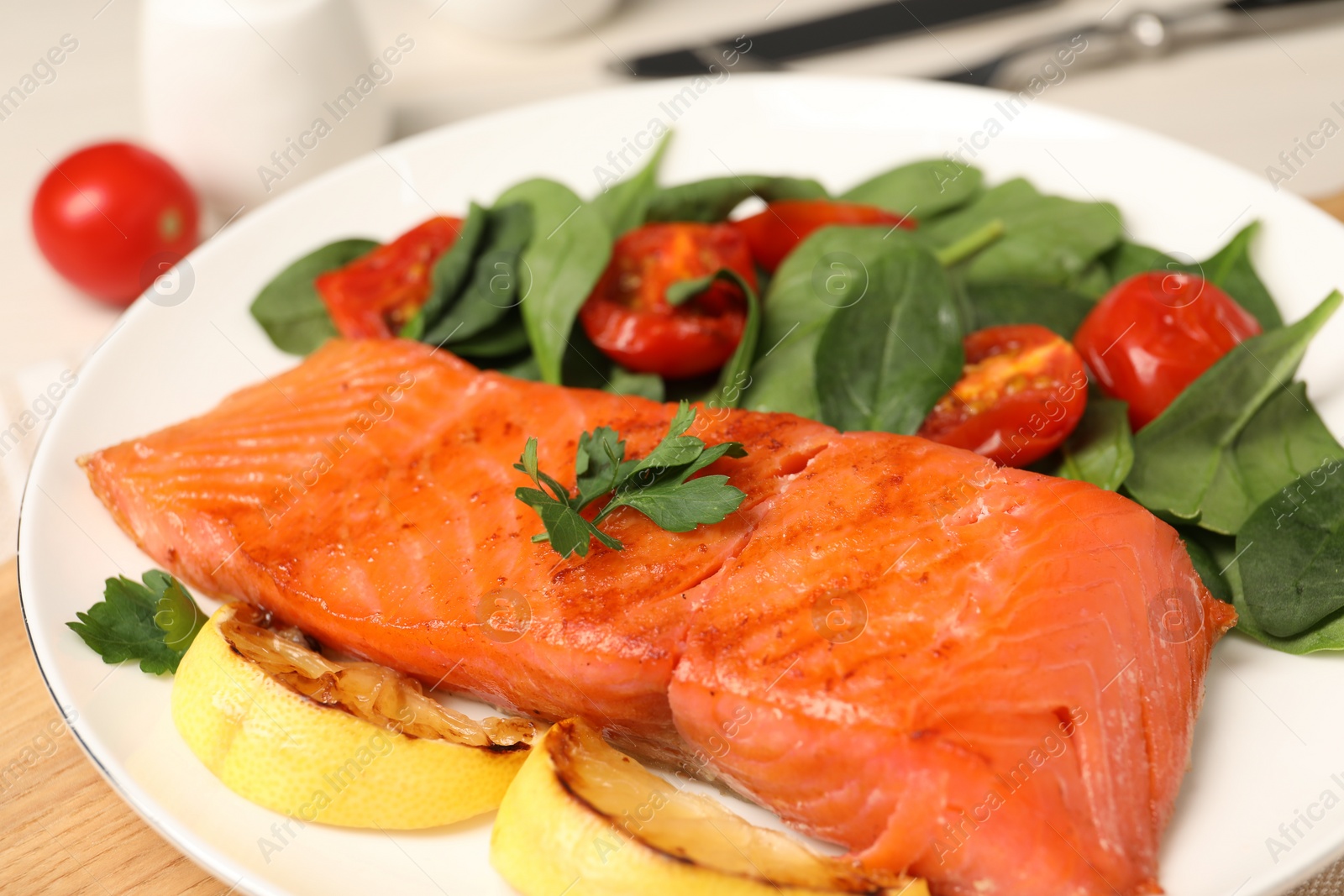 Photo of Tasty grilled salmon with basil, tomatoes and lemon on table, closeup