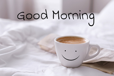 Aromatic coffee in cup with happy face on bed at home. Good morning