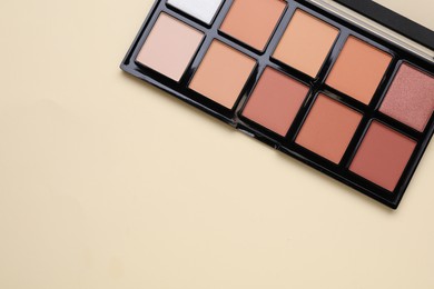 Colorful contouring palette on beige background, top view with space for text. Professional cosmetic product