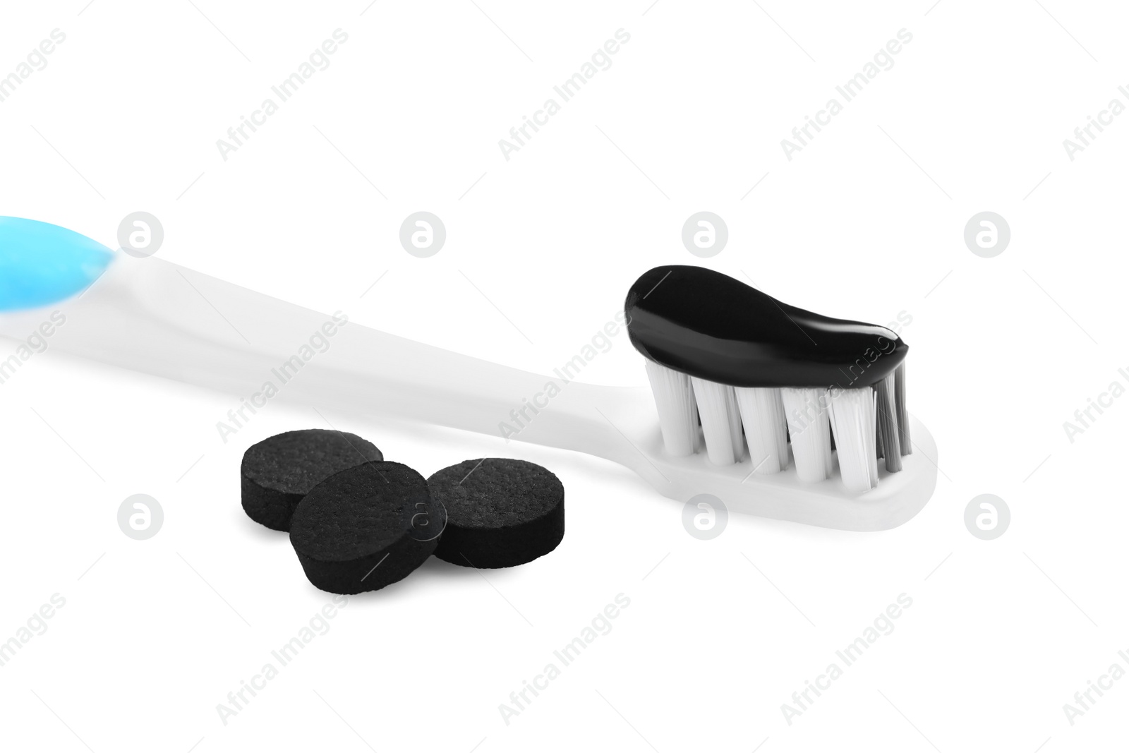 Photo of Brush with charcoal toothpaste and black pills on white background