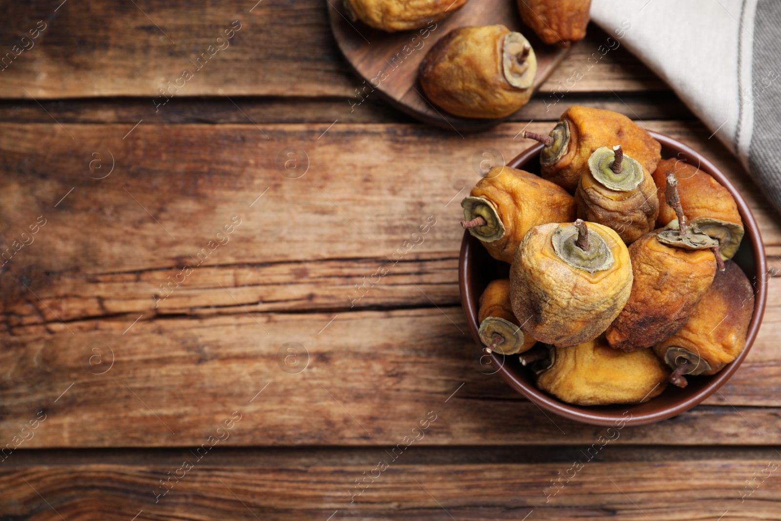 Photo of Bowl with tasty dried persimmon fruits on wooden table, flat lay. Space for text