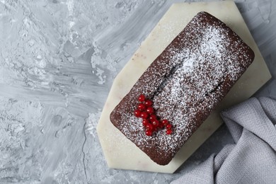 Photo of Tasty chocolate sponge cake with powdered sugar and currant on light grey textured table, top view. Space for text