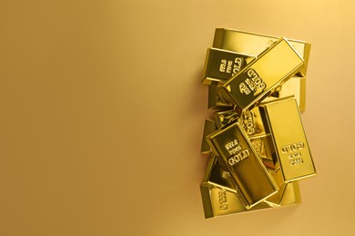 Photo of Many shiny gold bars on color background, flat lay. Space for text